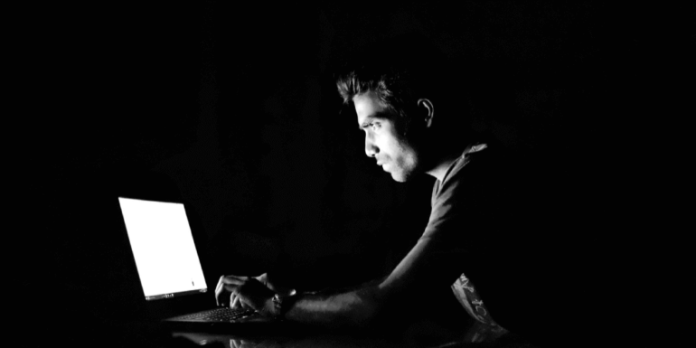 A man in the dark on a laptop.