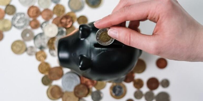 A person putting coins in a piggy bank.